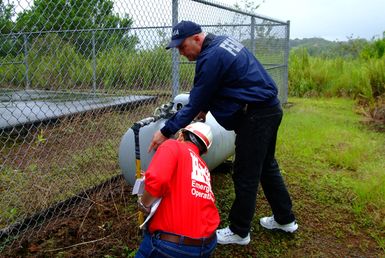 [Earthquake] Pepeekeo, HI, November 13, 2006 - FEMA Mitigation Map Mod. specialist Marshall Marik and U.S. Army Corps structural engineer Peter Lam inspect a gas line that provides energy to operate a police/fire communication tower. The FEMA coordinated mitigation inspection team was checking for a rupture in the line that may exist after a recent series of earthquakes. Adam DuBrowa/FEMA.