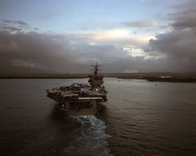 Aerial stern view of the nuclear-powered aircraft carrier USS ENTERPRISE (CVN 65) as it enters Pearl Harbor. Members of the crew man the rail