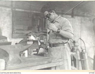 LAE BASE AREA, NEW GUINEA. 1944-12-04. QX42351 CRAFTSMAN J. MCDOWALL BRONZE WELDING THE CRANK HANDLE FOR THE UNIT "SOUTHERN CROSS" DIESEL ENGINE IN THE WORKSHOP OF THE 2/77TH LIGHT AID DETACHMENT