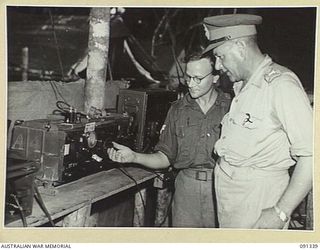 BOUGAINVILLE. 1945-04-27. MAJOR GENERAL C.H. SIMPSON, SIGNAL OFFICER IN CHIEF (2), BEING SHOWN A WIRELESS TRANSMITTER BY CORPORAL P.C.T. TAYLOR, 3 DIVISION SIGNALS (AIF) (1), DURING HIS VISIT TO ..