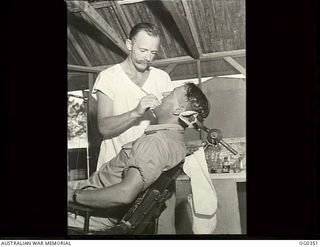 NEW GUINEA. C. 1944-05. RAAF DENTIST ATTENDING TO A PATIENT IN A DENTAL SECTION