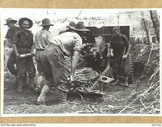 RAMU VALLEY, NEW GUINEA. 1943-12-25. MEMBERS OF NO. 8 BATTERY, 2/4TH FIELD REGIMENT ALL TAKING TURNS TO SEND OVER TWO ROUNDS OF 25 POUNDER SHELLS SIGNED "MERRY CHRISTMAS" INTO THE JAPANESE LINES AS ..