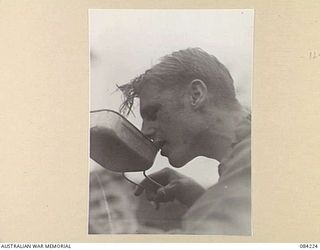 SUAIN PLANTATION, NEW GUINEA. 1944-12-06. PRIVATE R.N. ADDISON, DRINKING TEA FOLLOWING HIS RETURN FROM A PATROL WITH MEMBERS OF A COMPANY, 2/4 INFANTRY BATTALION