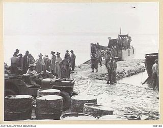 JACQUINOT BAY, NEW BRITAIN. 1944-12-04. HQ 5 DIVISION TROOPS LOAD TENTS INTO A BARGE FOR TRANSPORTATION TO 13 INFANTRY BRIGADE UNITS AT SWAN BEACH