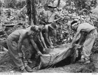 BOUGAINVILLE, SOLOMON ISLANDS. 1945-03-28. GUNNERS OF THE 5TH BATTERY, 2ND FIELD REGIMENT, ROYAL AUSTRALIAN ARTILLERY BURYING A JAPANESE SOLDIER WHO HAD UNSUCCESSFULLY ATTEMPTED TO DESTROY THEIR ..