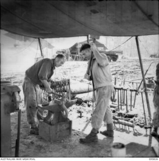 CAPE WOM, WEWAK AREA, NEW GUINEA. 1945-08-29. CRAFTSMAN W. DOWNS (1) AND CRAFTSMAN F. GASPARINI (2), AT WORK IN THE BLACKSMITH'S SHOP, 110 BRIGADE WORKSHOP, CORPS OF AUSTRALIAN ELECTRICAL AND ..