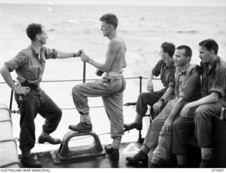 Troops of the 25th Infantry Battalion enjoying a yarn on the stern of the RAN frigate, HMAS Barcoo while on their way from Siar to Potsdam. They are, left to right: Q33494 Private (Pte) I N White; ..