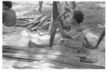 Woman preparing leaves for weaving?