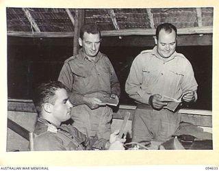SIPILANGAN, NEW BRITAIN, 1945-07-29. LIEUTENANT J.G. KINSEY, COMMANDING OFFICER, AUSTRALIAN NEW GUINEA ADMINISTRATIVE UNIT DISTRICT SERVICES TOL REFUGEE CAMP (1), WITH MEMBERS OF HIS STAFF. ..