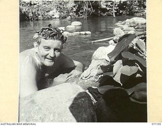 KILIGIA, NEW GUINEA, 1944-03-14. NX37475 LIEUTENANT R. S. DAWE, OFFICER COMMANDING 3RD ARMOURED DIVISION CONCERT PARTY, "SHELLSAPOPPIN", COOLING OFF IN A CREEK. LIEUTENANT DAWE IS THE MOST ..