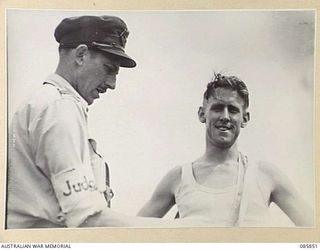 HERBERTON, QLD. 1945-01-19. SERGEANT MCHENRY, 2/23 INFANTRY BATTALION, (2), WHO DEAD HEATED WITH GUNNER BAIN, 2/12 FIELD REGIMENT, RECEIVES THE SASH FOR THE 880 YARDS SPRINT DURING THE 9 DIVISION ..
