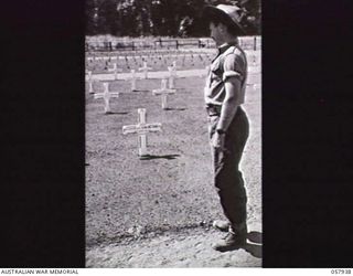 SOPUTA, NEW GUINEA. 1943-10-11. NX105018 PRIVATE B J GOSPER, HEADQUARTERS COMMAND, AUSTRALIAN ARMY SERVICE CORPS, INSPECTING THE GRAVE OF NX34853 CAPTAIN J M BLAMEY, NEPHEW OF THE COMMANDER IN ..