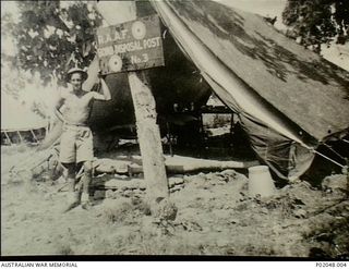 Port Moresby, New Guinea. 1943. Neville John Young leaning on a post outside his canvas tent sleeping quarters at RAAF Bomb Disposal Post No. 3. (Donor M Young)