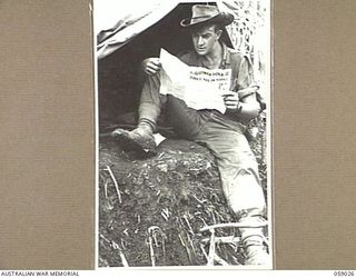 FARIA VALLEY, NEW GUINEA, 1943-10-17. NX127201 PRIVATE G. HAFEY OF THE 2/16TH AUSTRALIAN INFANTRY BATTALION, READING "GUINEA GOLD", AT HIS CAMP ON JOHN'S KNOLL. THE NEWSPAPERS WERE DROPPED BY ..