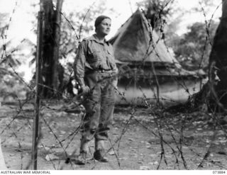 FINSCHHAFEN, NEW GUINEA. 1944-06-19. VFX94085 CAPTAIN NORA HEYSEN, OFFICIAL WAR ARTIST, MILITARY HISTORY SECTION, BEHIND THE BARBED WIRE PERIMETER AT THE NURSES' COMPOUND, 106TH CASUALTY CLEARING ..