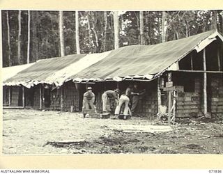 LAE, NEW GUINEA. 1944-03-29. MEMBERS OF THE 103RD FIELD AMMUNITION DEPOT FORMING NEW BUILDINGS AND STACKS OF AMMUNITION. THIS PICTURE INDICATES THE ORIGINAL STAGE OF THE STATIC DEPOT WHEN THE UNIT ..