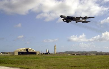 A US Air Force (USAF) B-52 Stratofortress, 2nd BW, Barksdale Air Force Base (AFB), Louisiana (LA), takes off past the tower and a hangar at Andersen AFB, Guam. The bomber is here supporting the 7th Air Expeditionary Wing's (AEW) mission