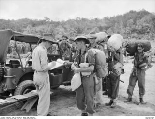 RABAUL, NEW BRITAIN, 1945-12-08. MEMBERS OF 11 DIVISION WITH HIGH PRIORITY FOR DISCHARGE, HAVE THEIR PAPERS CHECKED BEFORE EMBARKING ON HMAS WESTRALIA, FOR RETURN TO AUSTRALIA