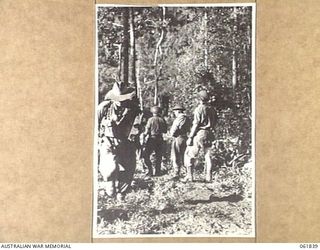 KOKODA TRAIL, NEW GUINEA. 1943-12-19. MEMBERS OF THE 2/9TH AUSTRALIAN INFANTRY BATTALION AND NATIVE CARRIERS ACTING AS EXTRAS DURING THE FILMING OF SEQUENCES FOR THE PRODUCTION, "RATS OF TOBRUK"