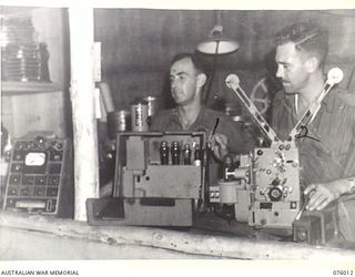 LAE, NEW GUINEA. 1944-09-18. STAFF SERGEANT H. NEWTON (1) AND VX11879 SERGEANT R. MARSDEN (2) VISUAL TRAINING SECTION HEADQUARTERS, NEW GUINEA FORCE, OVERHAULING UNIT MOVIE EQUIPMENT