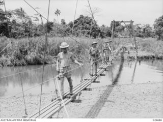MILNE BAY, PAPUA. 1942-10. AN AUSTRALIAN INFANTRY PATROL CROSSING A RIVER IN THE MILNE BAY AREA BY MEANS OF A SUSPENSION BRIDGE ERECTED BY 2/4TH FIELD COMPANY, ROYAL AUSTRALIAN ENGINEERS
