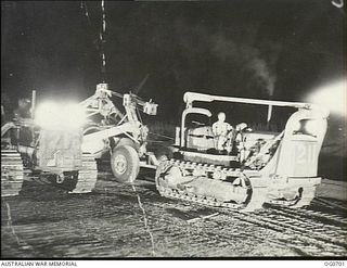 NADZAB, NEW GUINEA. C. 1944-02. NO. 62 MOBILE WORKS SQUADRON RAAF. TRACTORS HAULING GRADERS LEVELLING OFF THE AIRSTRIP AT NADZAB UNDER FLOOD LIGHTS AT NIGHT