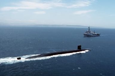 An Ohio class submarine travels out to sea as the miscellaneous flagship USS CORONADO (AGF-11) approaches Naval Air Station, North Island. The CORONADO, flagship for Commander, Third Fleet, will be arriving at its new home port after being stationed in Hawaii for almost 20 years