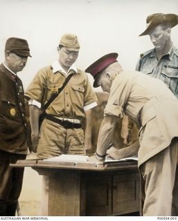 Major General H C H Robertson, GOC 6th Division, signing the surrender document marking the defeat of the Japanese, watched by the Commander of the 18th Japanese Army in New Guinea, Lieutenant ..