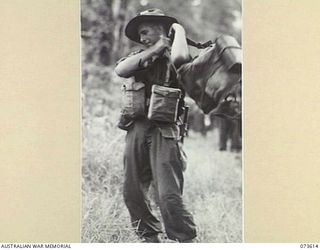 GAMAN, NEW GUINEA. 1944-05-27. N151860 PRIVATE H. MILTON, B COMPANY, 35TH INFANTRY BATTALION, SWINGS ON HIS PACK AFTER A PAUSE ON THE TRACK DURING THE ADVANCE ALONG THE COAST TOWARDS WEWAK