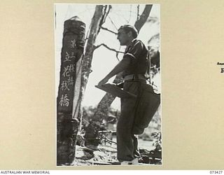 ALEXISHAFEN, NEW GUINEA. 1944-05-22. VX93432 CAPTAIN R. C. HODGKINSON (1), OFFICIAL WAR ARTIST, MILITARY HISTORY SECTION, SKETCHING A JAPANESE SIGN POST NEAR THE NORTH ALEXISHAFEN JETTY