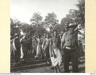 NEW GUINEA. 1944-06-29. NATIVE LABOURERS AT HEADQUARTERS NEW GUINEA FORCE BEING LED TO DUTIES BY AN NON COMMISSIONED OFFICER
