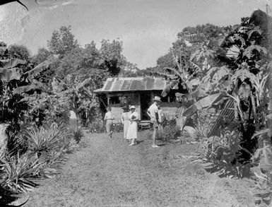 [Western and Pacific Island people in front of small building]