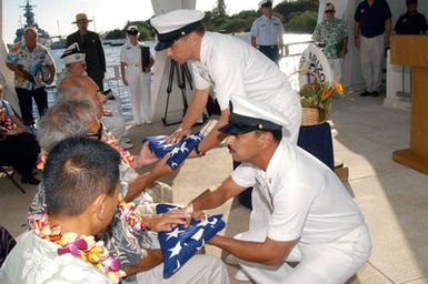 US Navy (USN) Command MASTER CHIEF (CMDMC) Luis R. Cruz, Navy Region Hawaii, and USN Force MASTER CHIEF (FORMC) Michael Banko, present flags to David and Tony Czarnecki, the sons of USN CHIEF Machinist's Mate (MMC) Anthony Francis Czarnecki during a burial at sea ceremony aboard the USS ARIZONA Memorial. USN MMC Czarnecki and his brother Stanley were among 36 sets of brothers assigned to ARIZONA during the December 7, 1941 attack on Pearl Harbor. USN MMC Czarnecki's brother was killed in the attack and his last wish was to be returned to USS ARIZONA to be with his brother and shipmates upon his passing