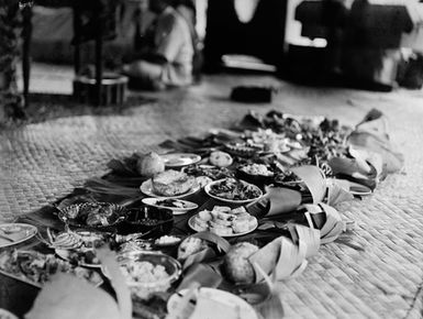 [Plates of food on flax mats on floor in Pacific Island location]