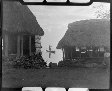 Two fales along a road at Faleolo, Apia, Upolu, Samoa, inlcluding a man on a canoe