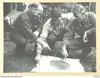DUMPU, RAMU VALLEY, NEW GUINEA, 1944-02-11. NX137271 PRIVATE R. WOOLBANK (2), PICTURED WITH A JAPANESE FLAG HE ACQUIRED DURING THE ATTACK ON MATELOI. WITH HIM ARE TWO OTHER MEMBERS OF "B" COMPASNUY ..