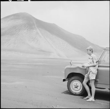 Young man leaning on a landrover with Mount Yasur in background, Tanna Island, Vanuatu / Michael Terry