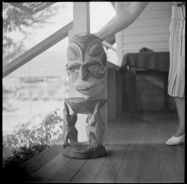 Three legged stool and a carved mask, held from behind, Awar [?], Sepik River, New Guinea, 1935 / Sarah Chinnery