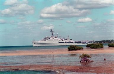 A port beam view of the Third Fleet flagship USS CORONADO (AGF-11) departing Pearl Harbor through the channel.