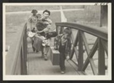 A family boards the SS Shawnee, Army Troop Transport, for the return trip to their former homes in Hawaii. 1100 evacuees of Japanese ancestry were returned aboard the Shawnee. Photographer: Mace, Charles E. Los Angeles, California