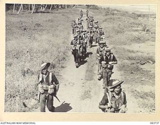 AITAPE, NEW GUINEA. 1944-11-23. A COMPANY OF 2/4 INFANTRY BATTALION TROOPS PASSING THROUGH A COCONUT PLANTATION DURING THEIR MARCH TO DRINIUMOR RIVER POSITIONS. IDENTIFIED PERSONNEL ARE:- PRIVATE ..