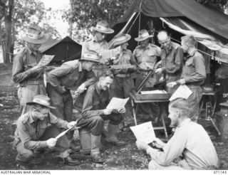 MASAWENG RIVER, NEW GUINEA, 1944-03-12. "THE PREMATURE BURST", A DAILY NEWSPAPER BEING READ BY MEMBERS OF THE 2/14TH FIELD REGIMENT. THE NEWS, TAKEN FROM THE SIGNAL SECTION RADIO, IS SUPPLEMENTED ..