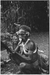 Pig festival, wig ritual, Tsembaga: decorated man holds feather valuable, smiling boy looks on