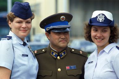 General (GEN) Yu of People's Republic of China poses for a photograph with two US Air Force Airmen as members of the Chinese People's Liberation Army Air Force Song and Dance Troupe board a US Air Force aircraft for a flight back to China. The troupe is here on the final stop of its US tour