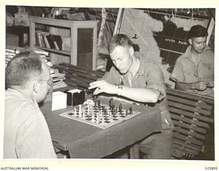 PORT MORESBY, PAPUA. 1942-07-11. A FIGHT WITHOUT NOISE. IN BETWEEN ALERTS, CAPTAIN W. BOYD OF OHIO AND LIEUTENANT R.W. SCHICK (FACING CAMERA) OF SAN FRANCISCO, MATCH THEIR SKILL ON THE CHESS BOARD. ..
