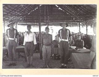 CAPE WOM, NEW GUINEA, 1945-12-01. LIEUTENANT TAZAKI (2) AND CORPORAL YAMAMOTO (3) GUARDED BY MEMBERS OF THE PROVOST CORPS, STANDING BEFORE THE COURT. LIEUTENANT TAZAKI WAS TRIED AND SENTENCED TO ..