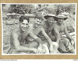 MILNE BAY, NEW GUINEA, 1943-07-12. MEMBERS OF THE 5TH AUSTRALIAN ARMY TROOP COMPANY TAKING A REST AFTER CARRYING HEAVY STEEL PIPES UP A HILL, ON THE MAPO ROAD. THEY ARE, LEFT TO RIGHT:- NX52838 ..