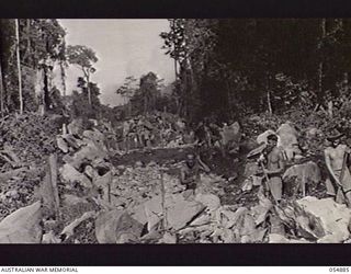 BULLDOG-WAU ROAD, NEW GUINEA, 1943-07-12. AUSTRALIAN ENGINEERS OF HEADQUARTERS, ROYAL AUSTRALIAN ENGINEERS, 11TH AUSTRALIAN DIVISION, CLEARING BLASTED ROCK AND SPREADING IT ON THE NEW ROAD AT THE ..