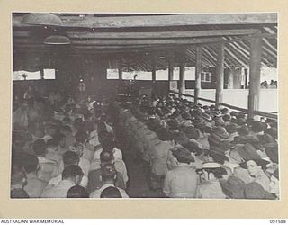 LAE, NEW GUINEA, 1945-05-09. HEADQUARTERS FIRST ARMY PERSONNEL SEATED IN THE GARRISON CHAPEL BEFORE THE COMMENCEMENT OF THE CHURCH OF ENGLAND AND OTHER PROTESTANT DENOMINATIONS THANKSGIVING ..