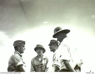 NEW BRITAIN, 1945-09. NEW ZEALAND AND JAPANESE OFFICERS, WITH AN INTERPRETER, TALKING IN THE RABAUL AREA. (RNZAF OFFICIAL PHOTOGRAPH.)